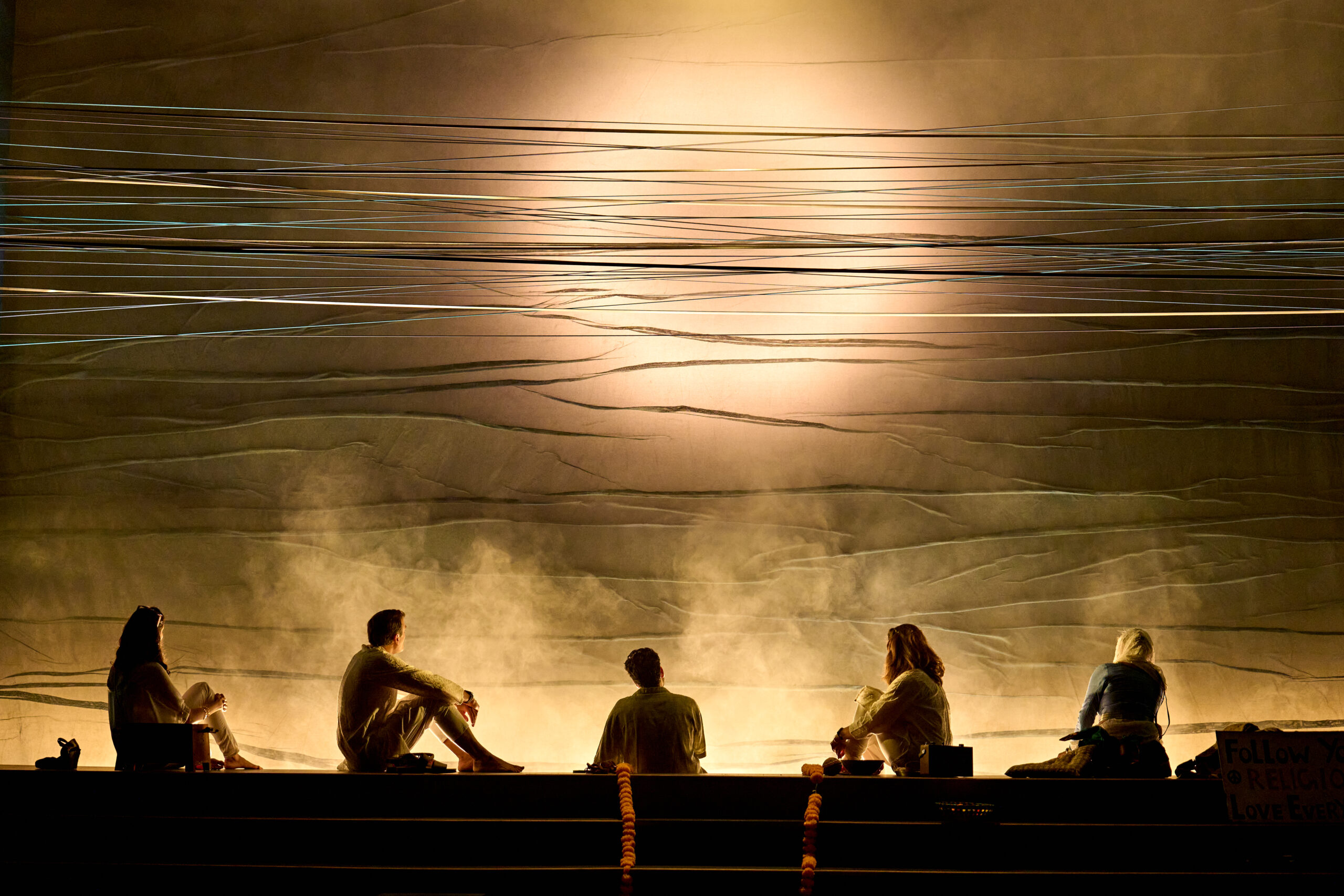 The cast of 'A Tupperware of Ashes' are backlit. They make silhouettes with telephone wires, backlit by a hazy sun.