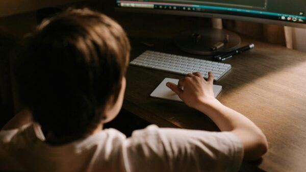 A boy sitting in front of a computer in the dark