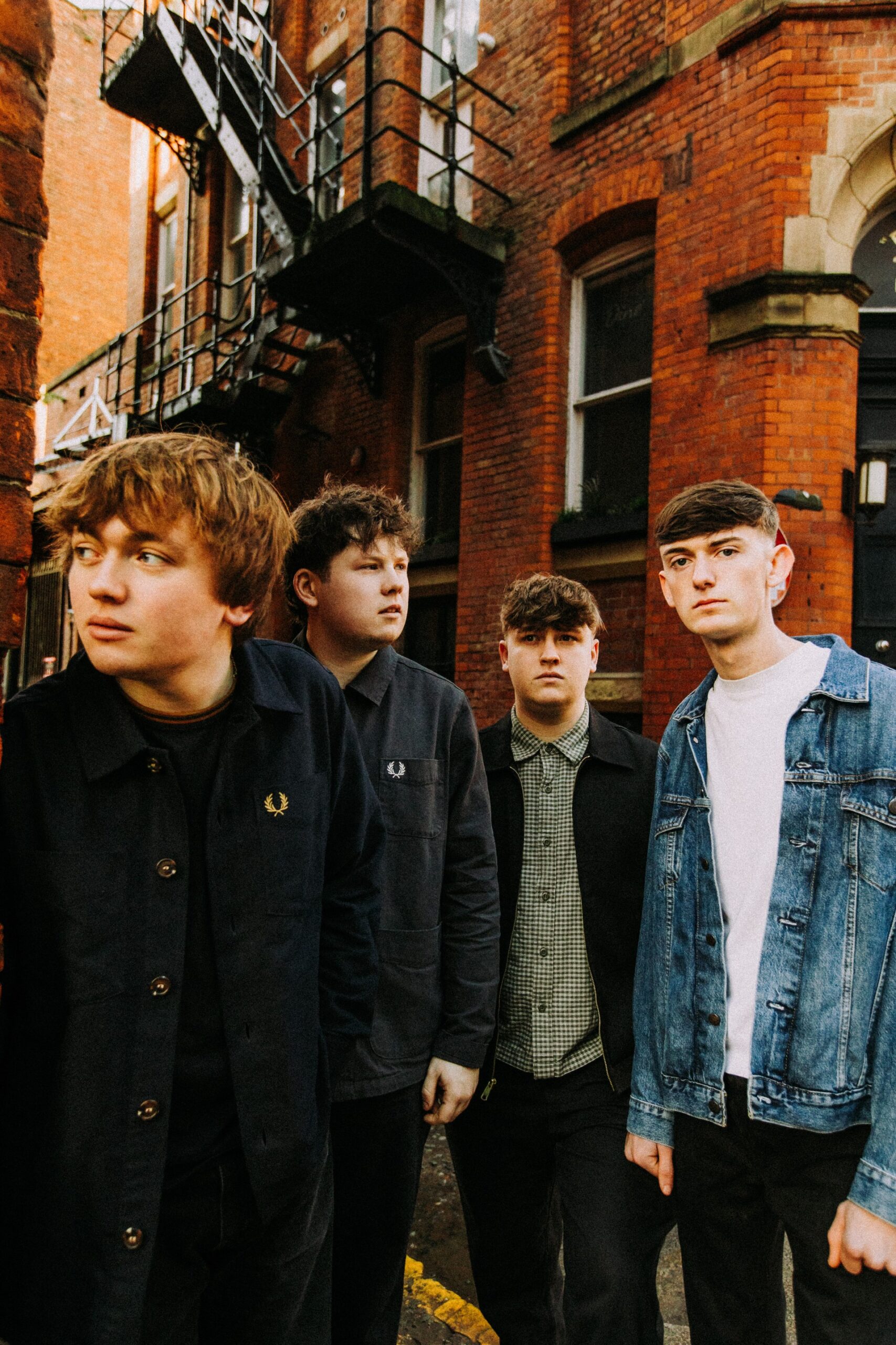 Members of 'The Cases' stand in front of a red brick building.