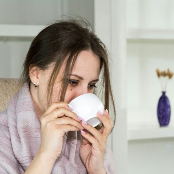 a woman sitting in a chair drinking from a cup